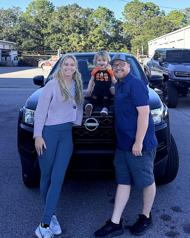 Jessy Stancher, owner of Sailfish Water Co, with his fianc&eacute;e Maddy and their daughter, standing in front of his truck.